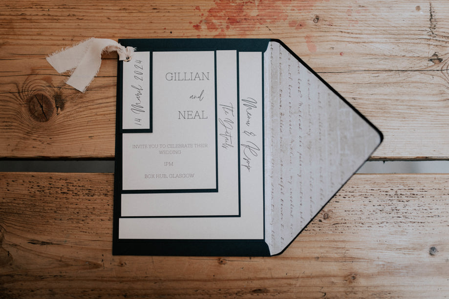 Black and white wedding invitation against wooden background